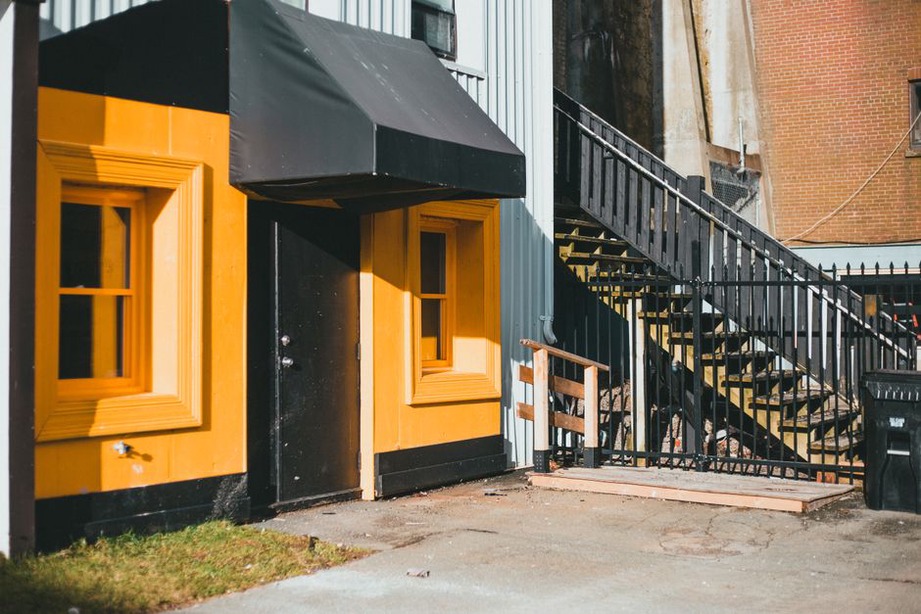 A covered entrance beside graded paving