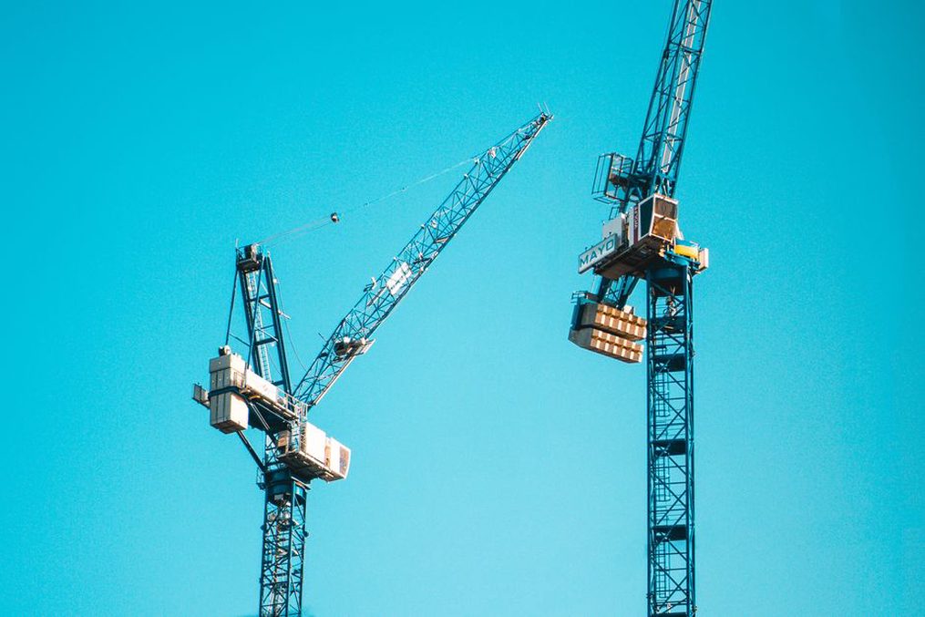 modular housing units suspended from crane hook during site assembly
